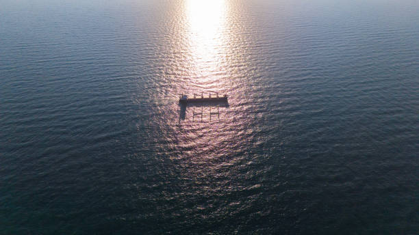 Aerial view of Seascape and silhouette general cargo ship floating in sea and over the sunlight background.