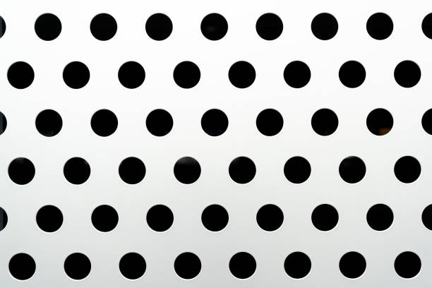 Metal background with holes. Steel plate with many circular holes drilled. Steel backdrop with holes. Stainless material with dots.