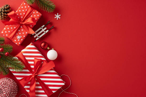 istock Brightly wrapped Christmas presents with red and white patterns, surrounded by festive decorations including pine cones and snowflakes, against a vivid red background creating a joyful holiday atmosphere 2181692418