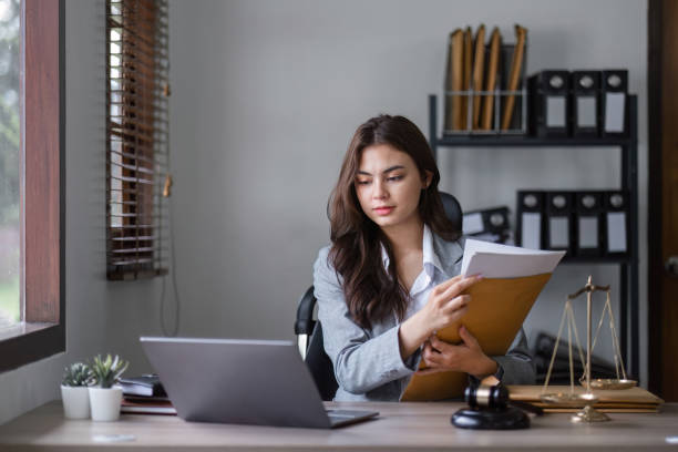 istock Young Businesswoman Analyzing Documents at Modern Office Desk with Laptop and Files for Professional Project 2181694413