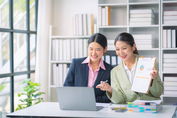 istock Two Asian businesswomen are deeply engaged in a discussion about data analysis work on a computer screen with graphs and charts. Showcase teamwork 2181696473