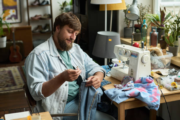 istock Man stitching detail to denim jacket 2181696553