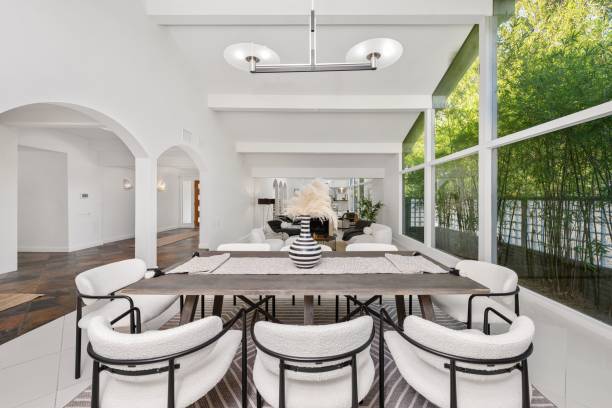 istock Modern dining room with elegant decor, featuring large windows and lush greenery 2181696765