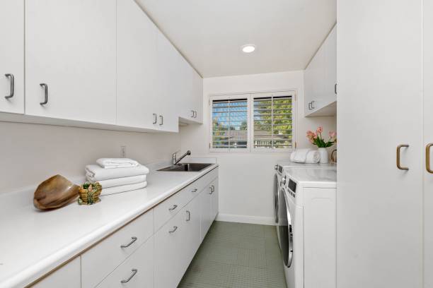 istock Modern laundry room with white cabinets, washer, dryer, and window view 2181696773