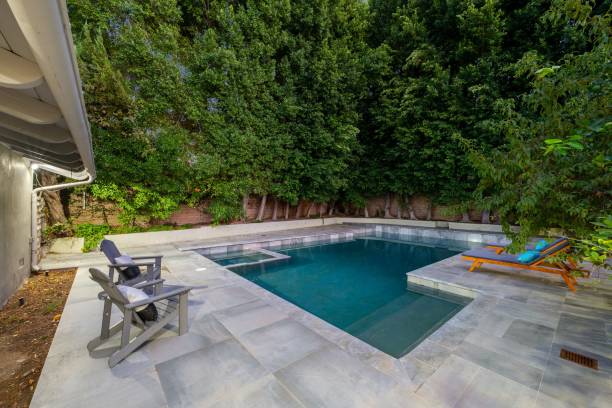 istock Modern backyard with a swimming pool, lounge chairs, and lush green trees 2181696828
