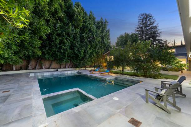 istock Modern backyard with a swimming pool, lounge chairs, and lush green trees 2181696861
