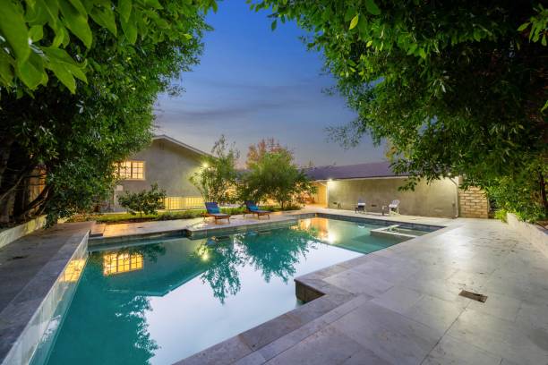 istock Modern backyard with a swimming pool, lounge chairs, and lush green trees 2181697281