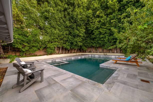istock Modern backyard with a swimming pool, lounge chairs, and lush green trees 2181697306