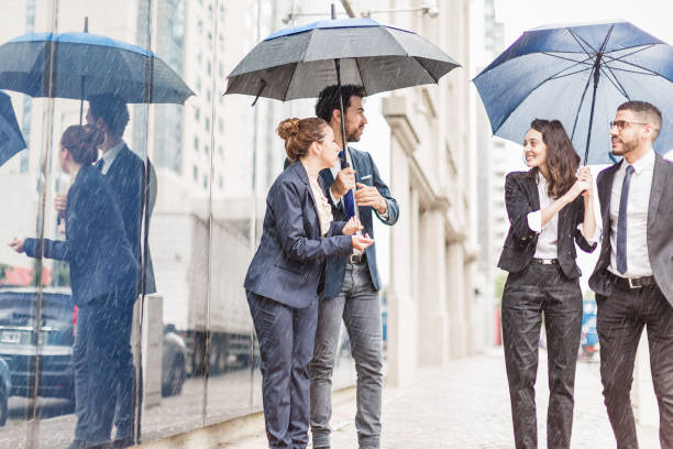 istock Business Professionals Walking in Rain with Umbrellas 2181698261