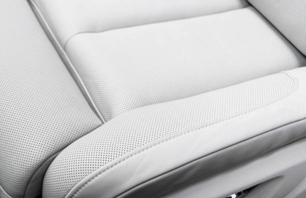 White leather interior of the luxury modern car. Perforated white leather comfortable seats with stitching. Modern car interior details.