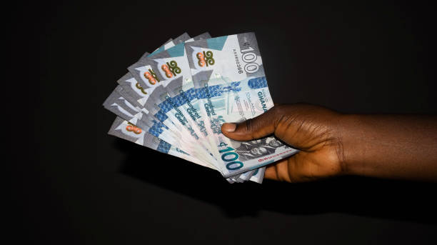istock Black hand holding  Ghana Cedis notes over dark background 2181705307
