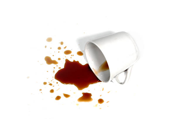 Close-up of coffee spilling from a white cup on white background