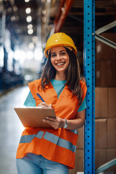 istock Female warehouse worker checking inventory and smiling at camera 2181711976