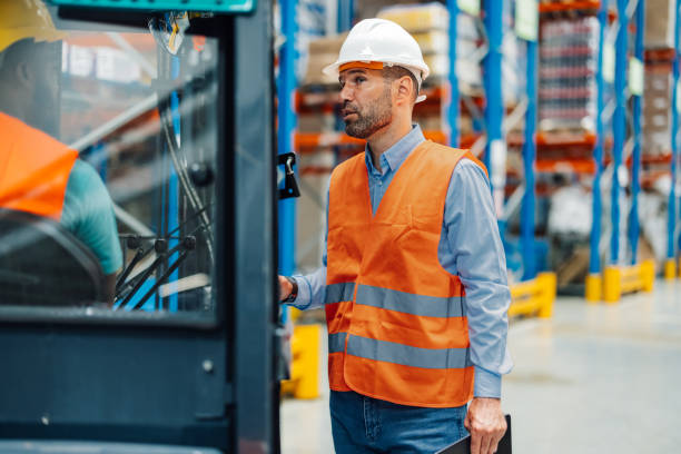 istock Supervisor holding clipboard talking to forklift driver in warehouse 2181712010