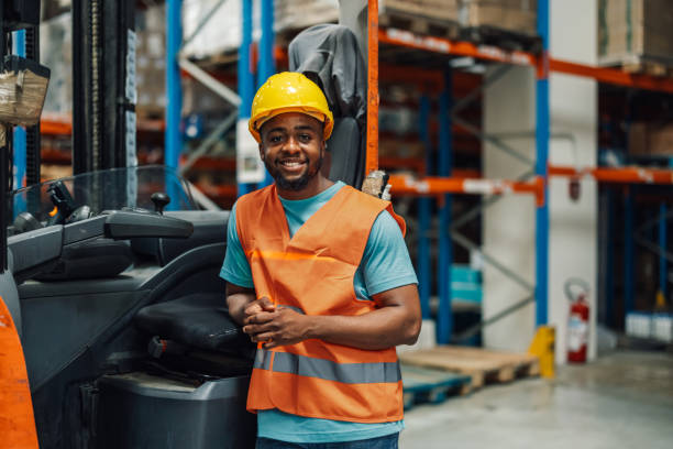 istock Smiling warehouse worker posing by forklift in busy warehouse 2181712019