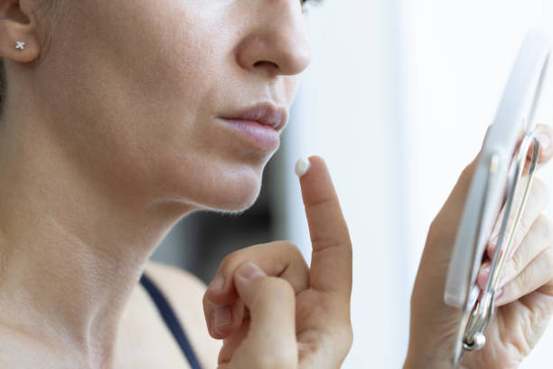 istock Woman looking at mirror and applying cream on dry lips. Closeup, selective focus. 2181714110