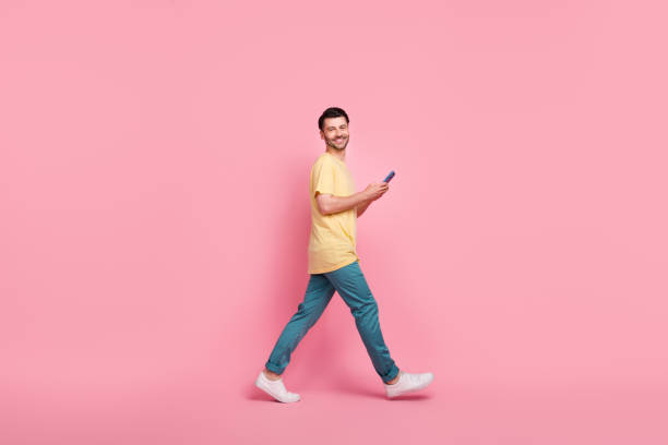 istock Full length profile side photo of good looking cheerful man go empty space read twitter facebook isolated on pink color background 2181720111