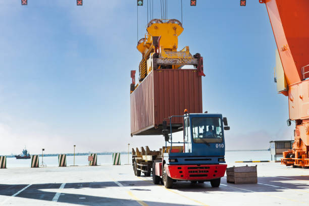 istock Crane lifting up container and loading truck in a port. 2181722521
