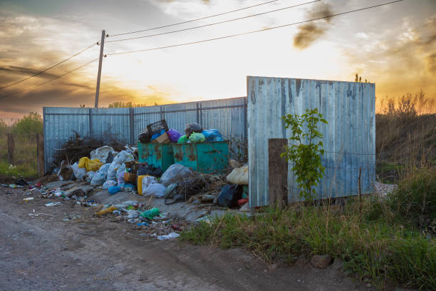 Krasnoyarsk, Russia - 28 May, 2022: Uncleaned trash cans full of different kinds of rubbish near allotment community garden in Russia. Environmental problems of modern consumer society.