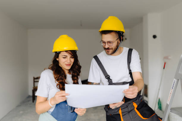 istock Man and woman construction workers in protection gear holding documents ant talking on indoor building construction site 2181724444