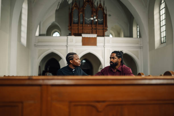 istock Priest listening to man talking while sitting in church 2181726530