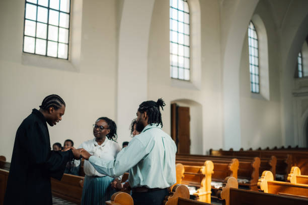 istock Priest holding hands with congregation members praying in church 2181729104