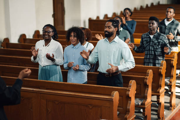istock Congregation standing and praying with arms raised in church 2181729105