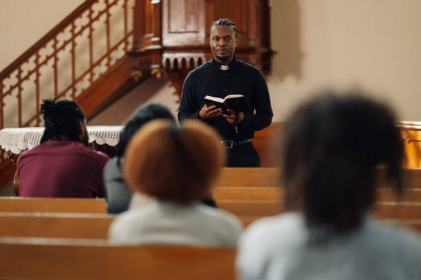 istock Young priest holding bible speaking to congregation in church 2181729155