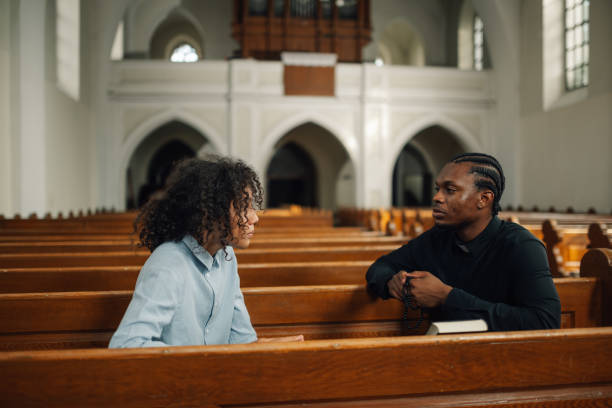 istock Young man talking to priest in church 2181729160