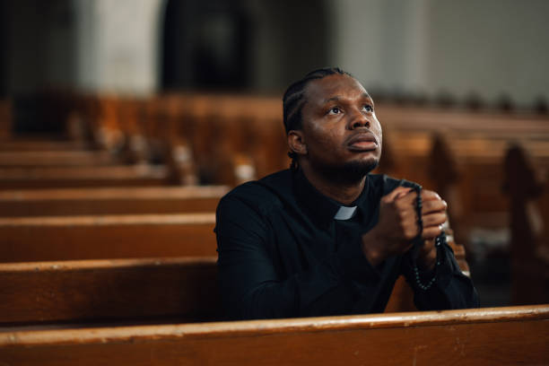 istock Priest praying with rosary beads in church pew 2181729183