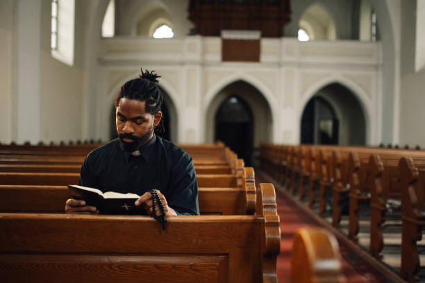 istock Priest reading holy bible and praying in church 2181729201