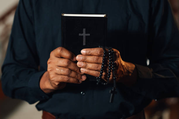 istock Priest holding holy bible and rosary beads praying 2181729258