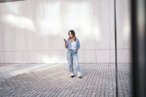 istock Casual woman standing and using smartphone outdoors 2181732980