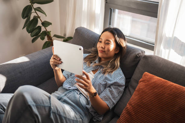 istock Asian woman relaxing on sofa using digital tablet at home 2181732994