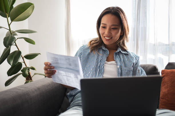 istock Smiling Asian woman working from home with laptop and documents 2181733016