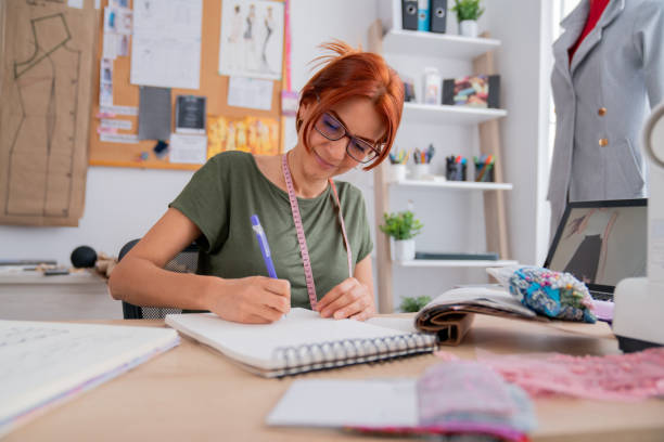 istock Fashion designer working at her atelier and writing on a notepad 2181733047