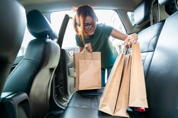 Happy Latin American female entrepreneur owning an e-commerce business and loading orders in her car for delivery