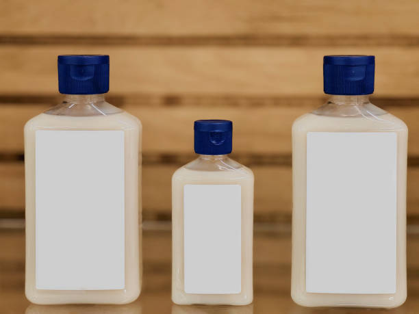 The image presents a series of four clear plastic bottles, each filled with a thick, creamy white substance and topped with a blue lid.