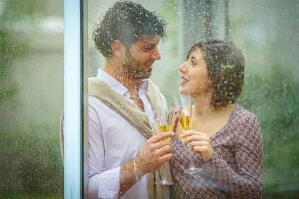 istock Romantic couple sharing a toast behind rainy window on wedding day 2181741856