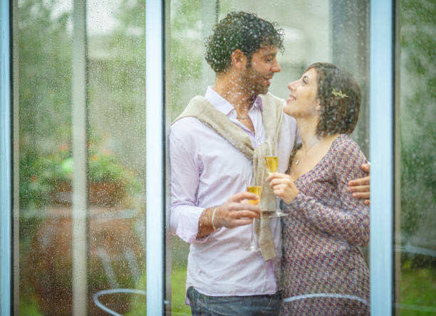 istock Romantic couple sharing a toast behind rainy window on wedding day 2181741867