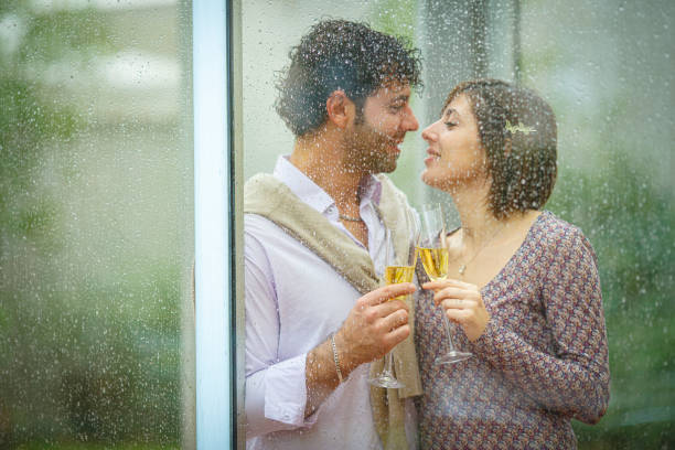 istock Romantic couple sharing a toast behind rainy window on wedding day 2181741877
