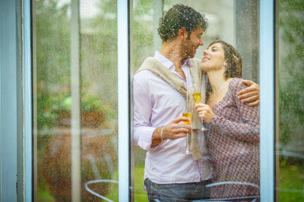 istock Romantic couple sharing a toast behind rainy window on wedding day 2181741952