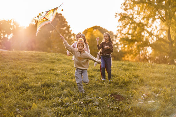 istock A boy runs with a kite with his friends in a meadow 2181743828