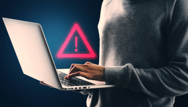 istock Person using laptop with red exclamation mark warning sign on dark background. Concept of digital error or attention. 2181745848