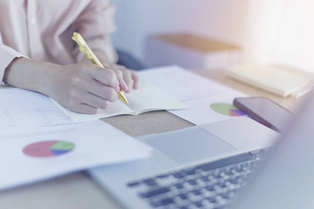 istock A woman with a focused expression, writing in a notebook with a 2181747938