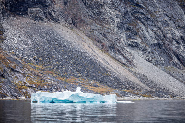 Iceberg in front of a rocky wall in a fjord outside Ilulissat in western Greenland which is an UNESCO World Heritage Site