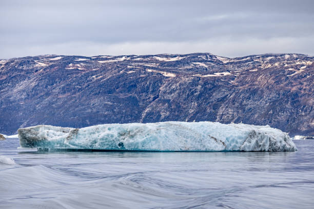 istock Iceberg floating in front of a rocky wall 2181750863