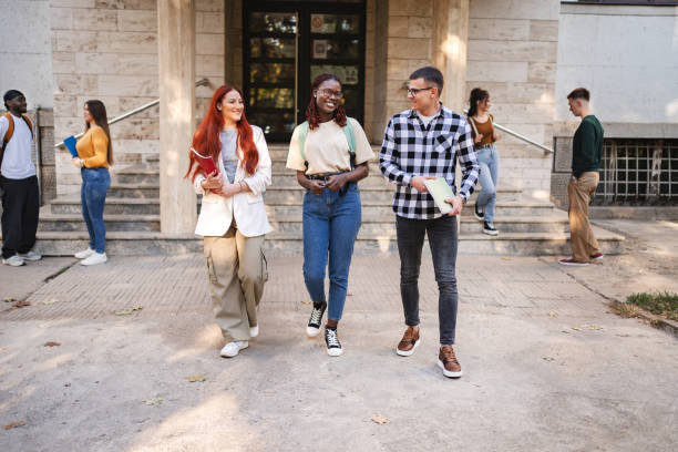istock Students engaged in lively conversation while walking outside their campus library during a sunny afternoon 2181750956