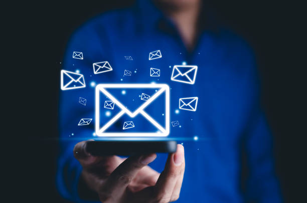 istock New email notification, online communication concept. A person holds smartphone with multiple glowing envelope icons floating, email notifications, and digital messaging. connectivity, eIectronic mail 2181751789