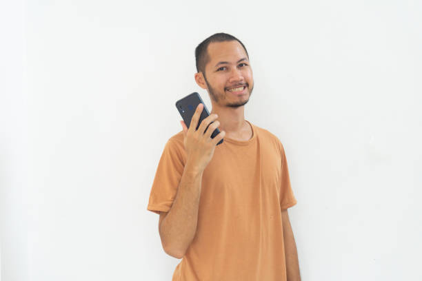 istock Young men wearing orange shirt is smiling using moble phone on isolated white background 2181753357